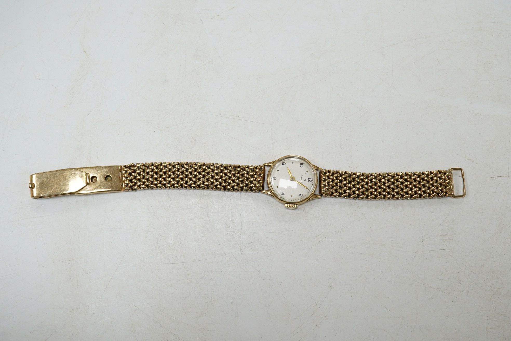 A lady's 9ct gold Omega manual wind wrist watch, on an associated 9ct bracelet, with Arabic and dot numerals, case diameter 20mm, overall length 16.7cm, gross weight 30 grams., no box or papers, with spare bracelet parts